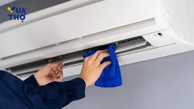 anh thợ cầm khăn xanh vệ sinh cánh máy lạnh