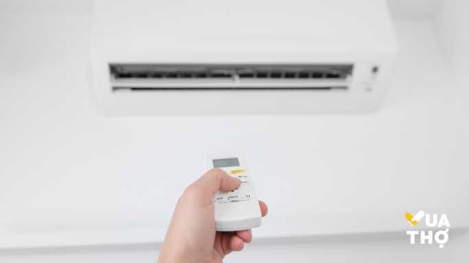 tay đang bật máy lạnh lên 