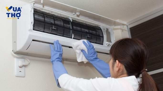 chị gái đeo găng tay xanh lau máy lạnh